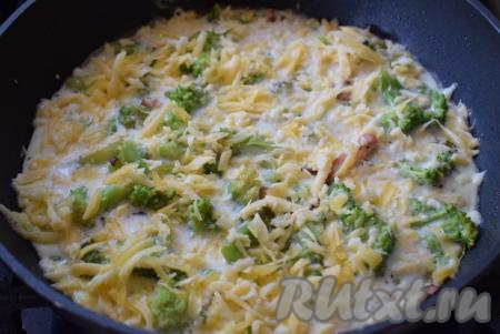 Как только яйца "схватятся", образовав легкую плотную шапочку, посыпаем омлет сыром, натертым на крупной терке.