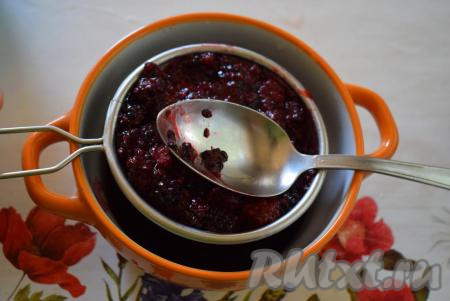 Процеживаем ежевичную массу через ситечко, протирая ягоды при помощи ложки.
