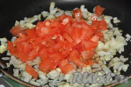 Мелко нарезать очищенный от шкурки помидор и добавить в сковороду к луку. Обжарить овощи, помешивая, в течение 3-5 минут на среднем огне.