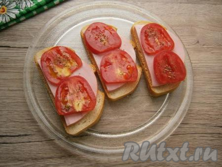 Ломтики вареной колбасы выложить на хлеб, а сверху - кружочки помидора, которые посыпать немного итальянскими травами.
