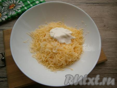 К сыру, натертому на мелкой или средней терке, добавить пропущенный через пресс чеснок и сметану, немного посолить. По желанию, вместо сметаны используйте майонез.