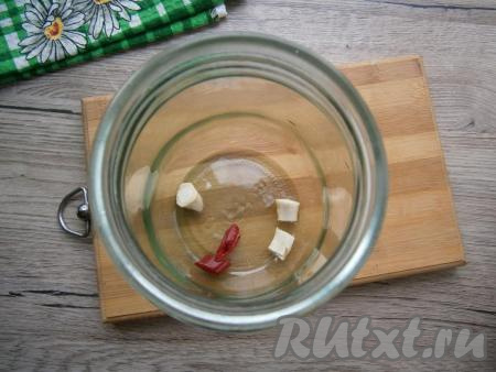 В чистую и сухую баночку выложить несколько&nbsp;кусочков корня хрена и пару колечек перца чили.