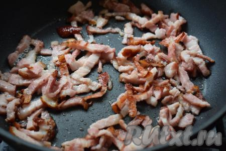 Разогреваем сковороду и наливаем в нее немного растительного масла. Добавляем нарезанный бекон и обжариваем его на среднем огне, помешивая, до золотистого цвета.