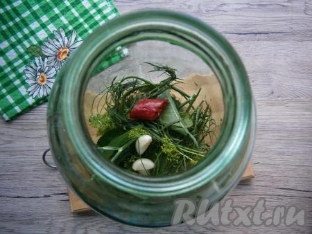 На дно чистых банок (банки не нужно стерилизовать) выложить очищенные зубчики чеснока, укроп, листья черной смородины и вишни, тархун и кусочек горького перца.