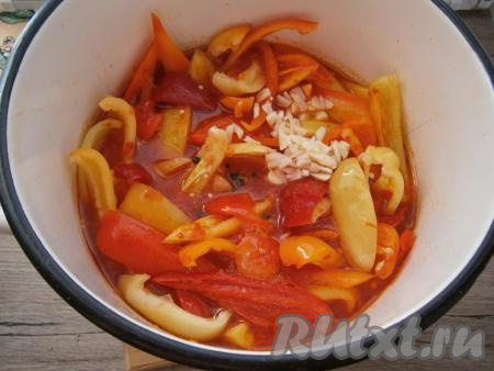 Добавить перец в кипящий томат. Сюда же добавить нарезанный мелко чеснок и горошины черного перца.