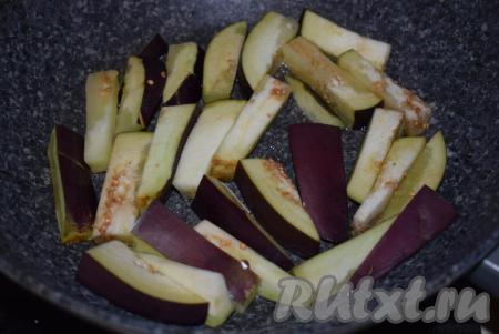 В сковороду щедро наливаем растительное масло и разогреваем его. Баклажаны, нарезанные на брусочки, выкладываем в сковороду в один слой и жарим на среднем огне под крышкой до румяного цвета с двух сторон и мягкости.