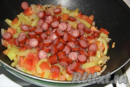 Колбасу нарезать на кусочки среднего размера, добавить в сковороду к овощам, хорошо перемешать и обжарить в течение минут 5, периодически помешивая.