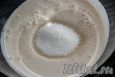 Затем в смесь кефира и соды всыпать сахар и перемешать.