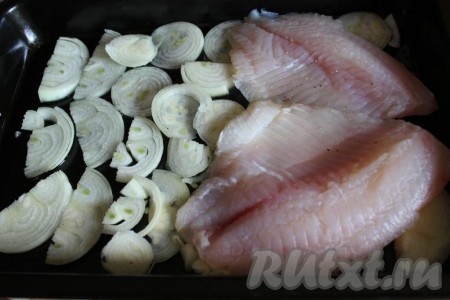 На смазанный растительным маслом противень положите слой нашинкованного лука и на него уложите филе тилапии.