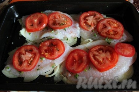 Зелень петрушки мелко порубите и посыпьте ею рыбу. Помидор нарежьте тонкими дольками и уложите на филе тилапии.