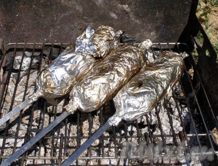 Развести огонь, дождаться, пока дрова прогорят и останутся только раскалённые "седые" угли (открытого огня быть не должно), выложить завёрнутые в фольгу шампуры с молодой картошкой и салом. Запекать, периодически переворачивая, 20-30 минут. За несколько минут до готовности снять фольгу, вернуть шампуры на мангал, чтобы картофель подрумянился.