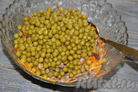 С горошка слить жидкость и добавить в салат из куриных сердечек, моркови и лука.