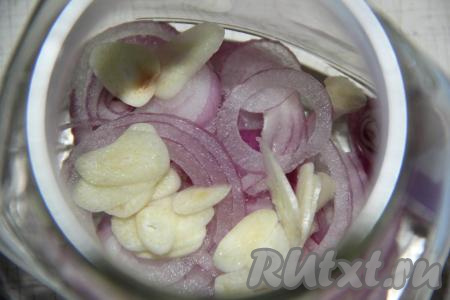 Затем слить с рыбы солевой раствор. Лук очистить и нарезать тонкими кольцами. Чеснок очистить и нарезать тонкими лепестками. Выложить лук и чеснок в банку.