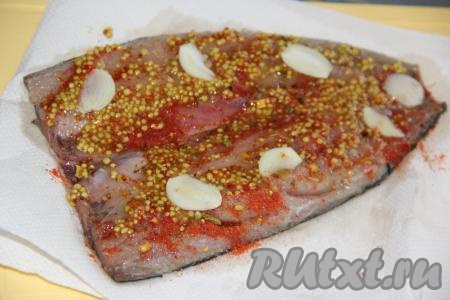 Очистить чеснок и нарезать его на тонкие лепестки. Выложить зерновую горчицу на филе скумбрии и равномерно распределить, затем разложить кусочки чеснока.