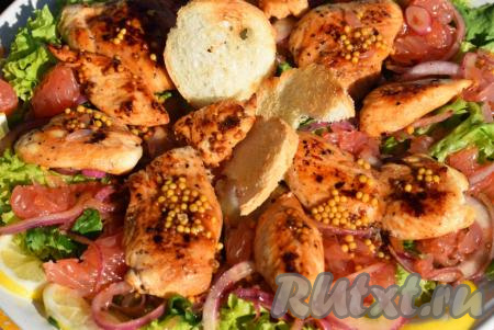 Готовые кусочки курицы выкладываем поверх грейпфрута и лука, поливаем каждый кусочек мяса оставшейся заправкой. Готовый салат с грейпфрутом и курицей подаем теплым к столу, украсив, по желанию, хлебными крутонами (подсушенными кусочками белого хлеба) и кружочками лимона.