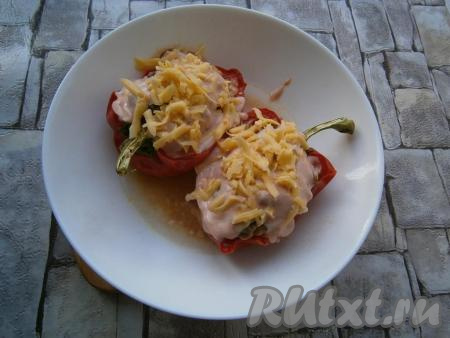 Далее вынуть фаршированный перец из микроволновки, если в тарелке нет совсем жидкости, добавить немного горячей воды. Полить перец приготовленным томатно-сметанным соусом и посыпать оставшимся тертым сыром.