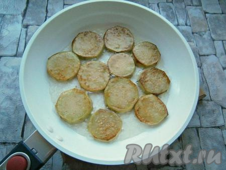 На сковороде разогреть растительное масло, выложить часть баклажанов (в один слой) и обжарить их на среднем огне до румяности с двух сторон. Обжаренные баклажаны выложить в миску, на сковороду отправить следующую порцию баклажанов, тоже обжарить их до румяности с двух сторон&nbsp; и выложить в миску. Таким образом обжарить все баклажаны.