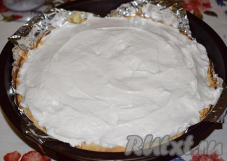 В этот момент достаем пирог и покрываем его сверху белками. Осторожно&nbsp;выкладываем белки на поверхность творожной начинки, разглаживая их ложкой.