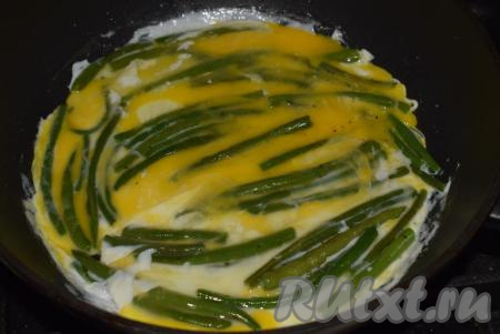 К обжаренной стручковой фасоли вбиваем яйца и распределяем их по всему периметру сковороды,&nbsp;накрываем крышкой и даем блюду протомиться на среднем огне около 3-4 минут (до готовности яиц).