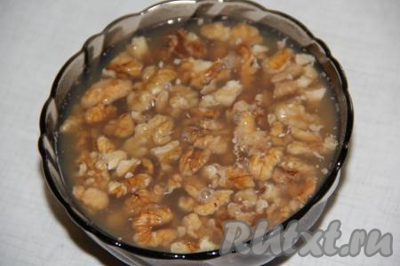 Ядра грецких орехов крупно порубить и залить горячим кипятком на 10 минут. Орешки распарятся и лучше в дальнейшем впитают сироп.