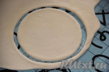 На столе, припыленном мукой, раскатать тесто (слишком тонко раскатывать не нужно, но раскатанный пласт теста не должен быть и толстым), с помощью большой кружки вырезать кружочки.