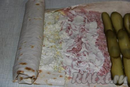 Подвернуть края лаваша со всех сторон и завернуть в плотный рулет.