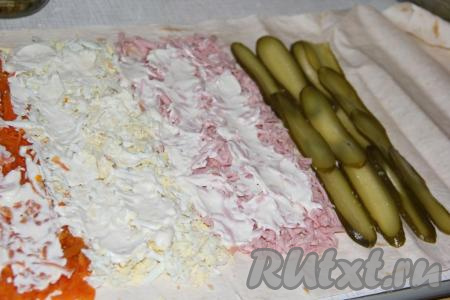 Огурчики нарезать тонкими пластами и выложить после колбасы.