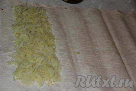 Картофель предварительно сварить в кожуре до готовности и остудить. Очищенную картошку натереть на крупной тёрке и выложить на лист лаваша полоской шириной, примерно, 10 см, оставляя края лаваша чистыми.