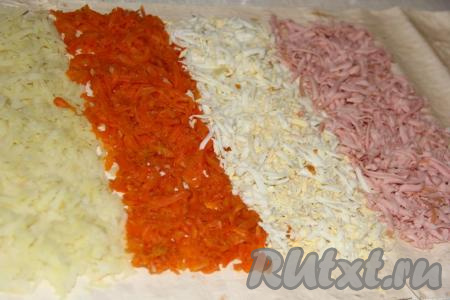 Дальше пришла очередь колбаски. Натереть варёную колбасу на тёрке и выложить после яиц. Все полоски получатся примерно одной ширины.