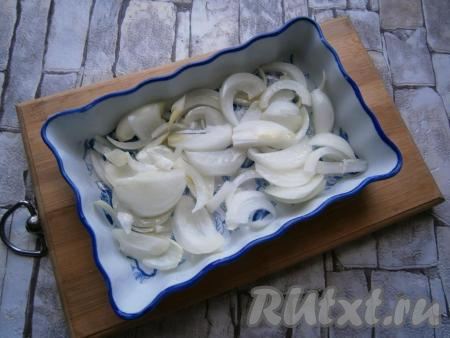 В небольшую форму для запекания выложить очищенный и нарезанный произвольно репчатый лук, полить его растительным маслом.