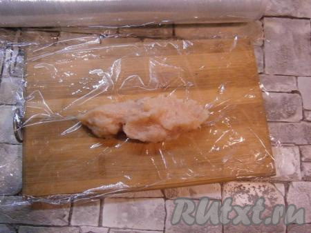 На кусок пищевой пленки выложить&nbsp;1-2 столовых ложки куриного фарша.