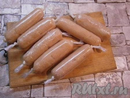 Свернуть пленку с фаршем, формируя плотную сосиску длиной около 10-12 см. Края пленки скрутить с каждой стороны и завязать в узел. Таким образом сформировать все сосиски. У меня их получилось 7 штук.