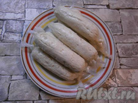 Сосискам, приготовленным из куриного филе, дать немного остыть, а затем снять пищевую плёнку. Подавать их можно сразу.