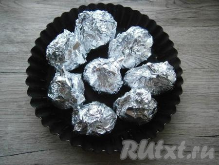 Завернуть каждую картофелину плотно в фольгу, закручивая ее сверху, поместить в форму для запекания или на противень.