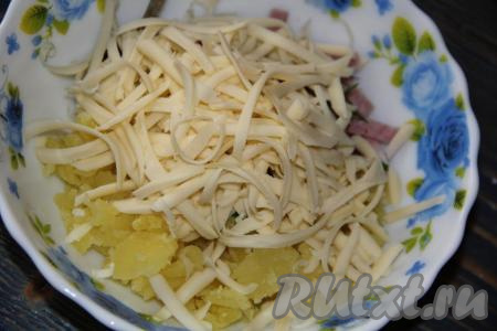 Сыр натереть на тёрке и добавить в начинку из картошки, зелени и ветчины.