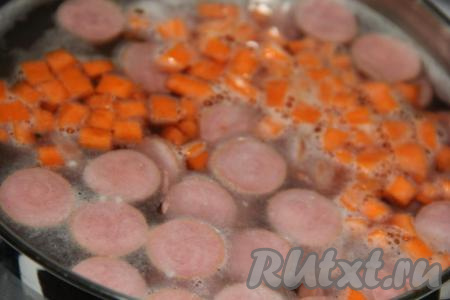 Как только суп с сосисками закипит, добавить в кастрюлю морковь и варить минут 10-15 с момента закипания на небольшом огне.