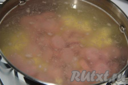 В кастрюлю влить 2 литра воды. Довести воду до кипения и добавить в кастрюлю нарезанные картофель и сосиски.