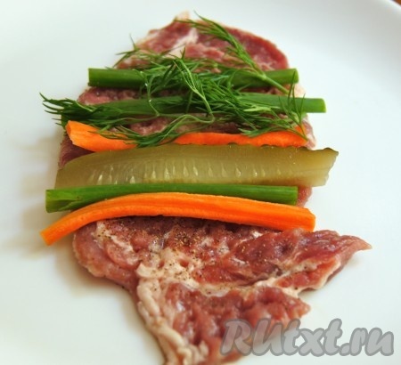 На отбитый стейк кладем огурец, лук, морковь, укроп.