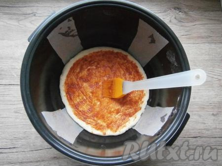 Тесто обмять, разделить на 2 части. Одну часть теста раскатать в лепешку диаметром с чашу мультиварки (вторую часть теста оставить под полотенцем). Из пергамента вырезать 2 полоски, каждая полоска должна быть шириной около 5-6 см и длиной около 45-50 см. Чашу мультиварки немного смазать растительным маслом. Вырезанные полоски разместить крест-накрест в чаше мультиварки (полоски бумаги нужны для того, чтобы готовую пиццу без проблем извлечь из чаши мультиварки). На дне чаши разместить лепешку из теста, которую смазать томатным соусом (или кетчупом).