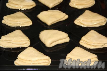Край круга смазать маслом и сложить ещё раз (как на фото), выложить заготовки на небольшом расстоянии друг от друга на противень, смазанный маслом.