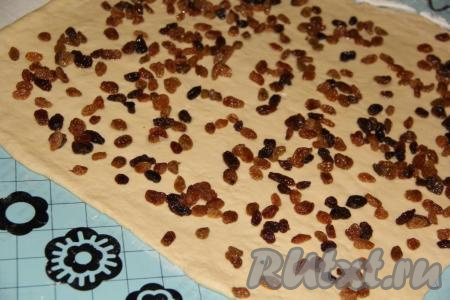 Выложить запаренный изюм на тесто и равномерно распределить по всей поверхности.