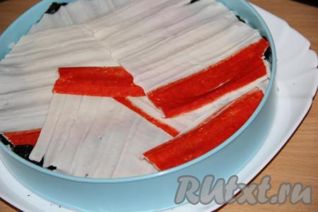 Далее выложить слой раскрученных крабовых палочек.