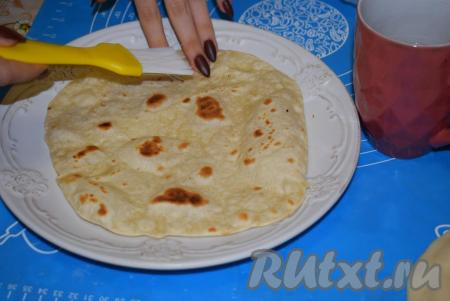 Готовый лаваш снимаем со сковороды, выкладываем на тарелку и быстро смазываем его водой при помощи кулинарной кисти с двух сторон.