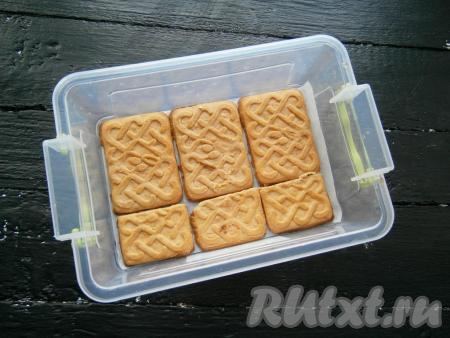 Дно формы застелить пергаментом и чуть смазать кремом, выложить слой печенья.