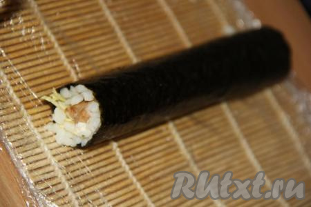 Аккуратно свернуть лист нори с начинкой в плотный рулет, начиная сворачивать с того края, на котором выложен рис. Чистый край листа нори я смазала водичкой (благодаря смазыванию листа нори водой, ролл с курицей хорошо скрепится и получится более красивым и ровным).