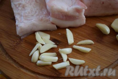 Чеснок нарезать на длинные полоски - так им легче будет шпиговать кусочки сала.