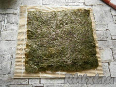 Лист нори вместе с рисом перевернуть (удобно переворачивать с помощью еще одной циновки, накрыв ею рис и просто перевернув).