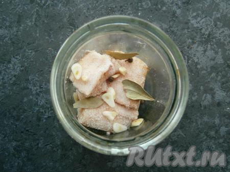 Далее складывать куски сала в чистую сухую банку, пересыпая пластинами чеснока, горошинами душистого перца и лавровыми листьями.