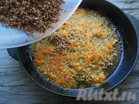 К обжаренным овощам выложите промытую гречневую крупу, перемешайте.