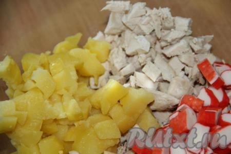 Картошку, сваренную в мундире, остудить, очистить, нарезать на кубики среднего размера и выложить к нарезанному куриному мясу.